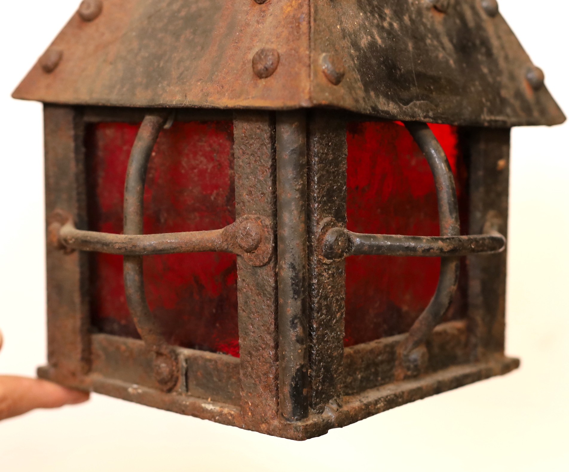 An early 20th century English wrought iron lantern with a red glass panels, height 29cm. width 20cm